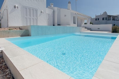 Kleiner Pool mit heller Folie und weißer mediterraner Hausfassade